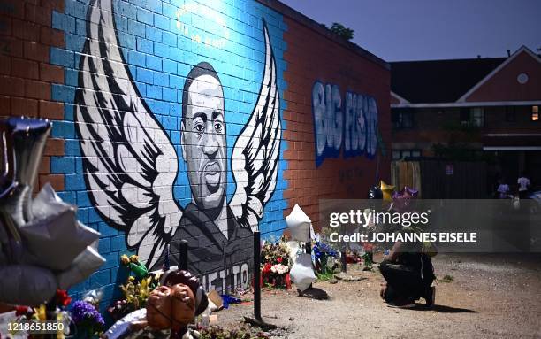 Man pays his respects and kneels in front of a mural of George Floyd in Houston, Texas on June 8, 2020. - Democrats vowed June 7, 2020 to press...