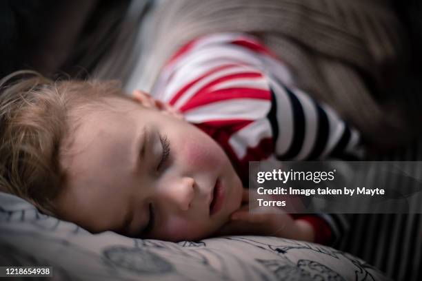 little boy peacefully sleeping in sofa - sick child stockfoto's en -beelden