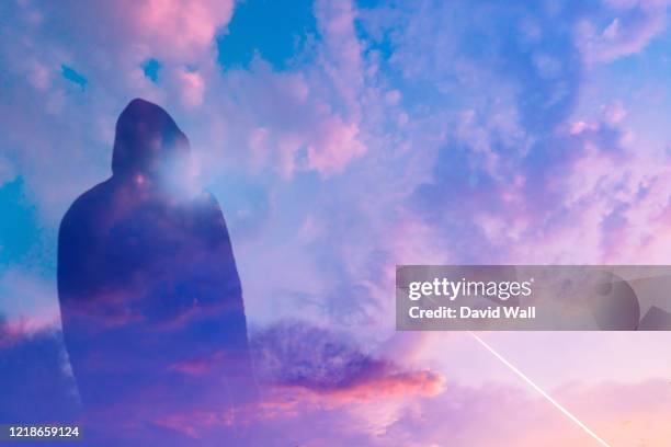 a double exposure of a moody, hooded figure silhouetted against the sunset. with deliberate lens flare.. with an abstract, experimental dream like edit. - sunset with jet contrails stock pictures, royalty-free photos & images