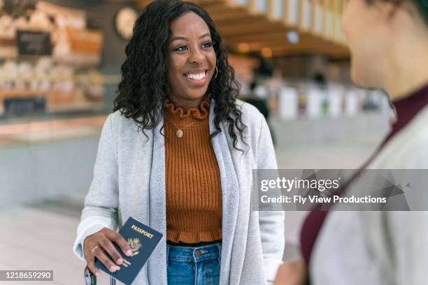woman holding passport talks with friend while waiting at airport - canada passport stock pictures, royalty-free photos & images