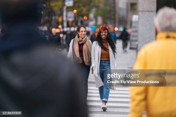 two beautiful women crossing busy city street - toronto people stock pictures, royalty-free photos & images