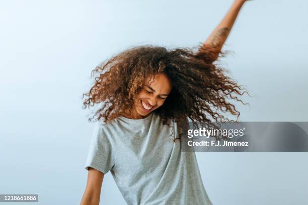 portrait of woman dancing in front of white wall - afro frisur stock-fotos und bilder