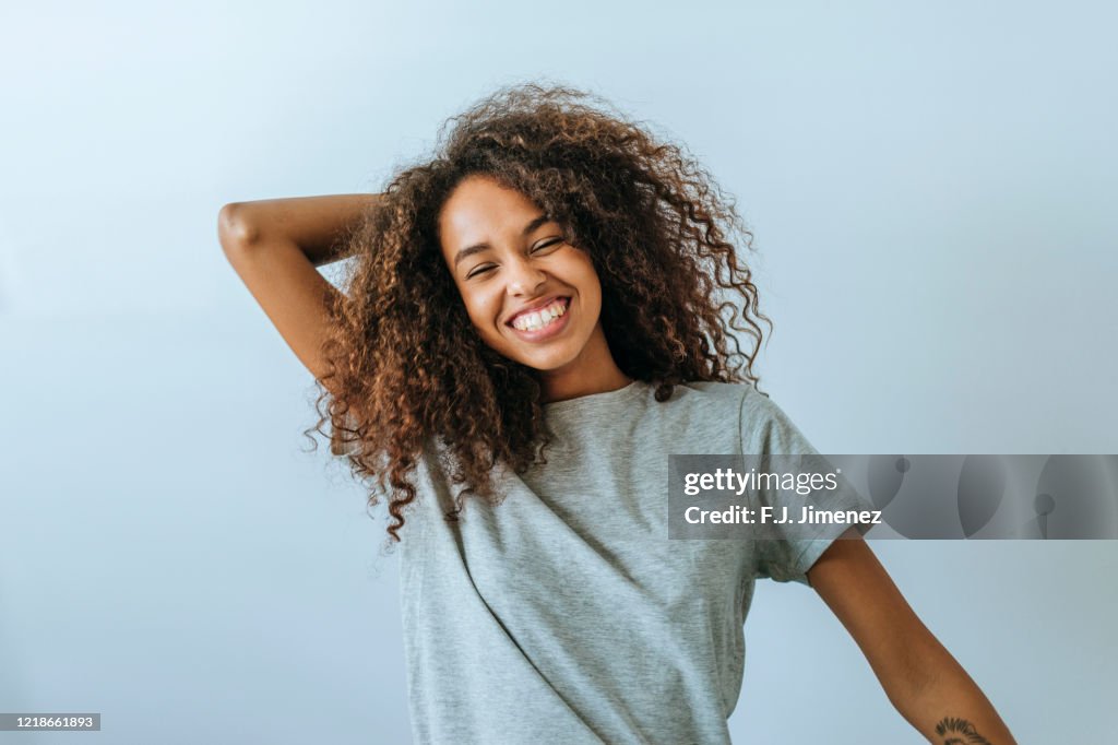 Portrait of woman with afro hair smiling with white wall background