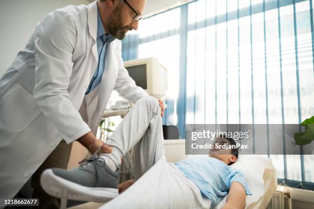 醫生檢查男孩膝蓋的流動性 - orthopedics 個照片及圖片檔