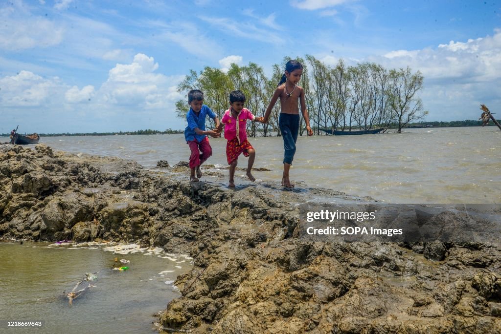 Children are seen walking through a muddy walk way at the...