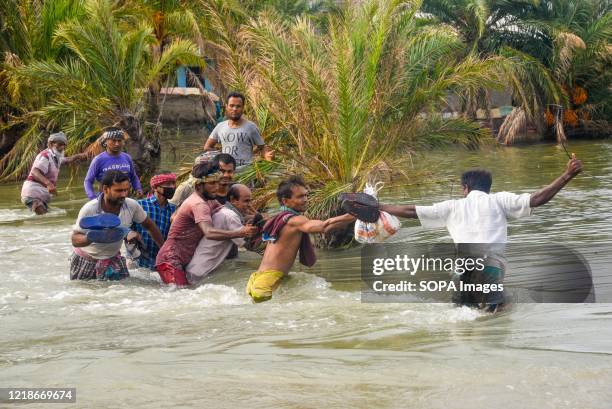 People crossing the broken flooded road after the landfall of cyclone Amphan during the aftermath. Thousands of shrimp enclosures have been washed...