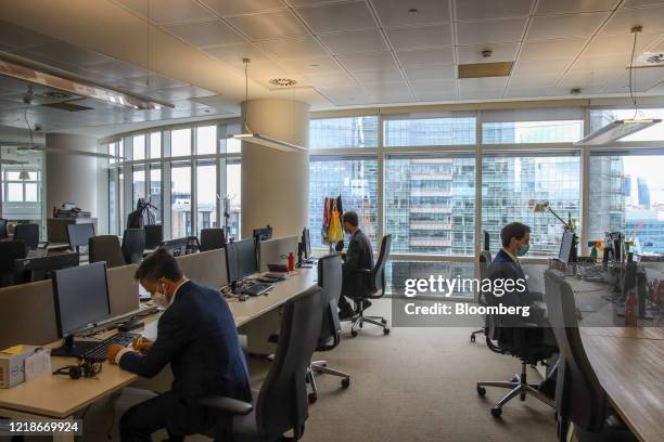 Employees wearing protective face masks sit at alternate desk, as part of social distancing measures, at the Unicredit SpA headquarters in Milan,...