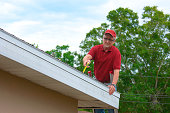 Wind mitigation inspection inspector on a ladder doing inspection on new roof to generate a risk rating