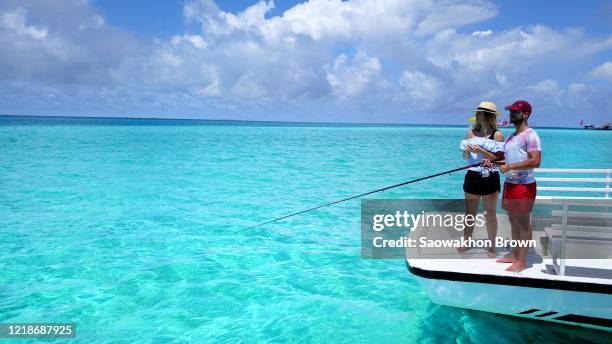 close shot of man and woman fishing together on luxury white boat, surrounded with clear water in maldives - protection luxe stock-fotos und bilder