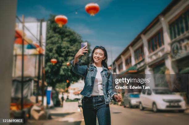 een jonge aziatische chinese meisjestoerist in penang, maleisië, zuidoosten azië dat foto in de straat met haar mobiele telefoon neemt - penang stockfoto's en -beelden