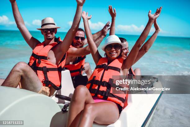 friends lifting their arms up during pedal boat fun on sea - pedal boat stock pictures, royalty-free photos & images