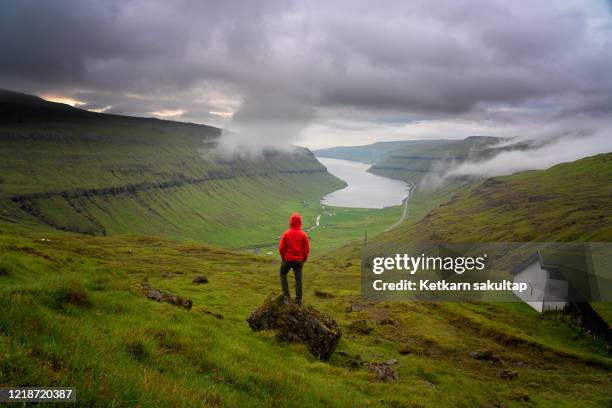 a man is admiring a scenic view of faroe islands landscape. - faroe islands stock pictures, royalty-free photos & images