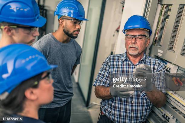 electrician teaching his apprentices how to strip the wires - electrical safety stock pictures, royalty-free photos & images