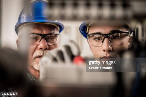 männlicher lehrling, der drähte in der verteilertafel verbindet - electromonteur stock-fotos und bilder