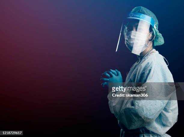 doctor in ppe suit uniform has stress and pray in coronavirus outbreak or covid-19, concept of covid-19 quarantine.emotional stress of overworked doctor and medical care team during covid-10 period. - abbigliamento da lavoro foto e immagini stock