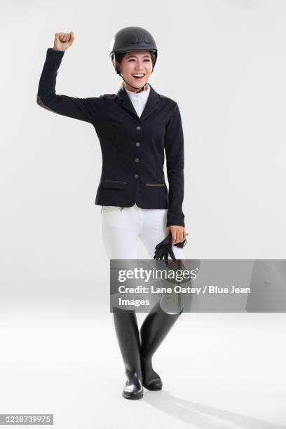 happy young chinese woman in riding clothes punching the air - woman jockey stock pictures, royalty-free photos & images