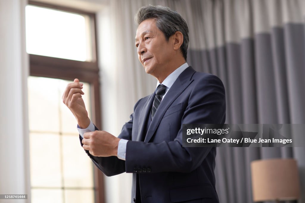 Senior Chinese man getting dressed at home