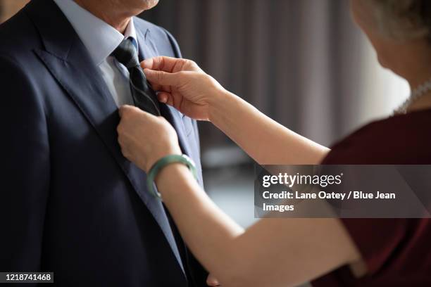 happy senior chinese woman tying husband's tie - krawatte stock-fotos und bilder