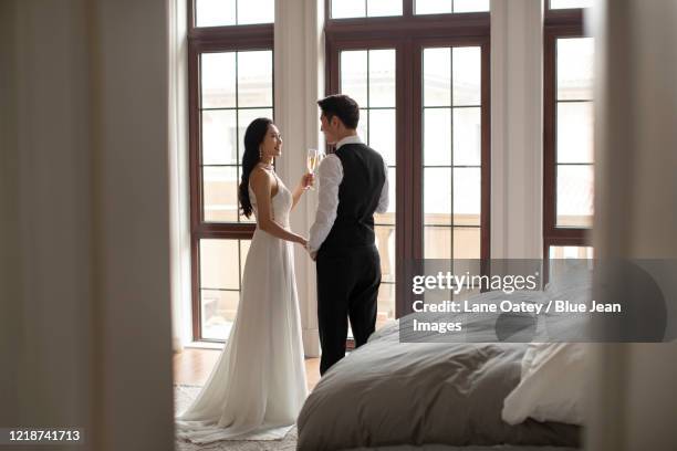 happy young chinese couple drinking champagne at home - avondkledij stockfoto's en -beelden