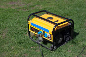 Powerful portable gas or diesel generator to provide electricity. Standing on the grass