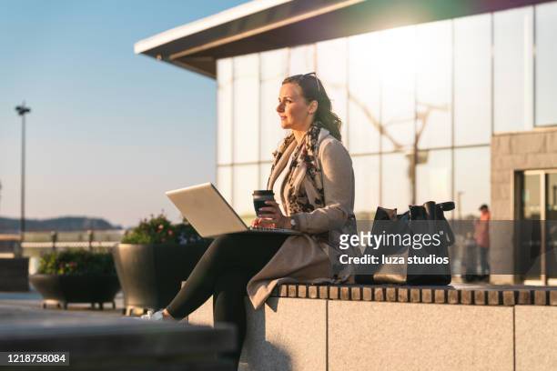 woman with laptop drinking coffee from a travel mug - goteborg stock pictures, royalty-free photos & images
