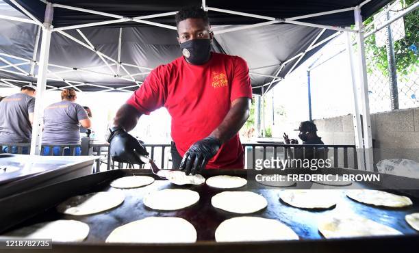 John Jones III flips tortillas in preparation for the Taco Tuesday meals given away to children and families in the Watts neighborhood of Los...