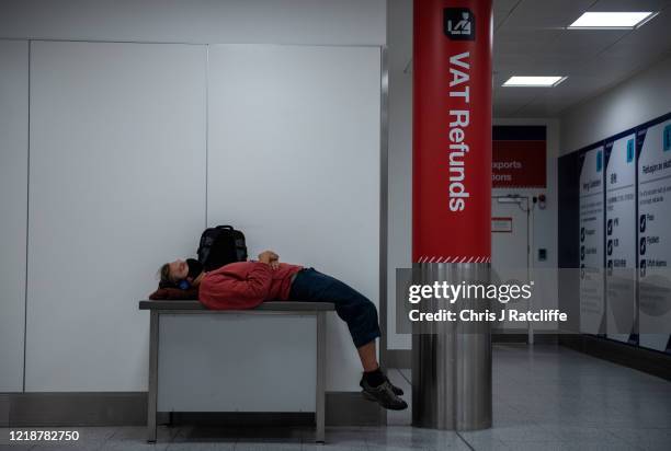 An airline passenger lies on a table next to the VAT refunds area inside the South Terminal at Gatwick Airport on June 9, 2020 in London, England....