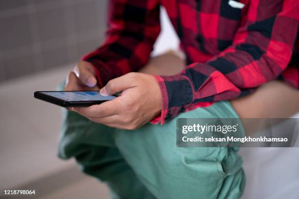 man using a smart phone while sitting on the toilet - public restroom stock pictures, royalty-free photos & images
