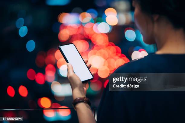 young woman using smartphone in busy downtown district against urban skyscrapers with multi-coloured neon signs and busy city traffic - traffic jam billboard stock pictures, royalty-free photos & images