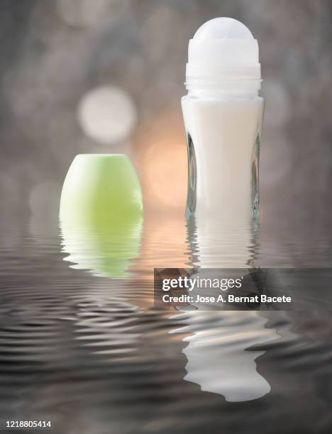 glass deodorant container with roll on ball on a water surface illuminated by sunlight. - deodorant photos et images de collection