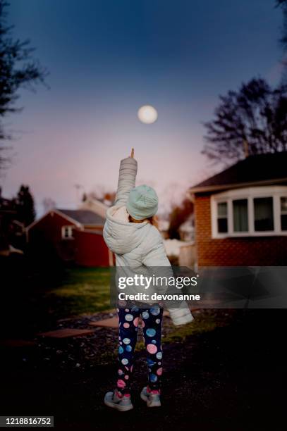 meisje dat leggingleggings van het ruimtethema draagt die bij de maan staren - girl full moon stockfoto's en -beelden