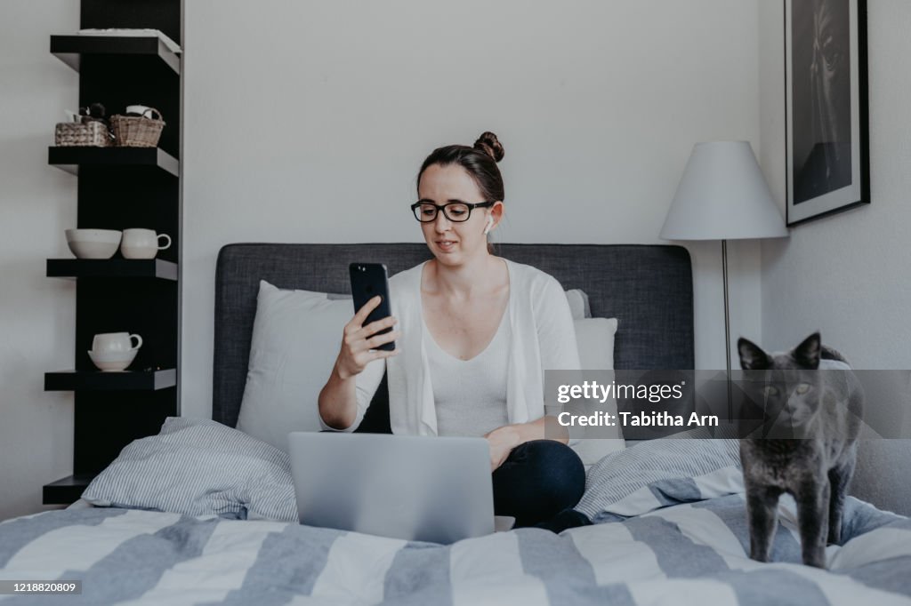 Frau arbeitet von zu Hause im Home Office mit Airpods drahtlosen Bluetooth Kopfhörer mit Katze Haustier