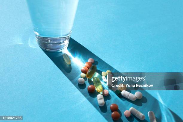 glass with various pills on the blue background - homöopathie stock-fotos und bilder