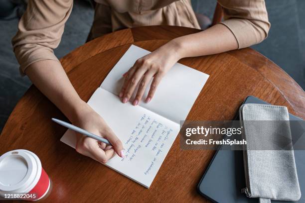 hands of an anonymous woman writing notes in her notebook, a close up - poeta imagens e fotografias de stock