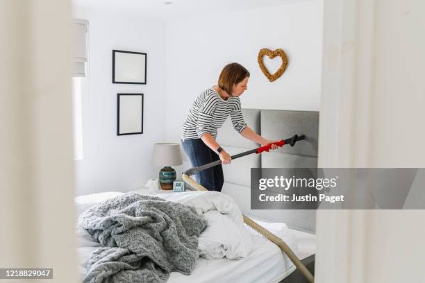 woman deep cleaning her bedroom - headboard stockfoto's en -beelden