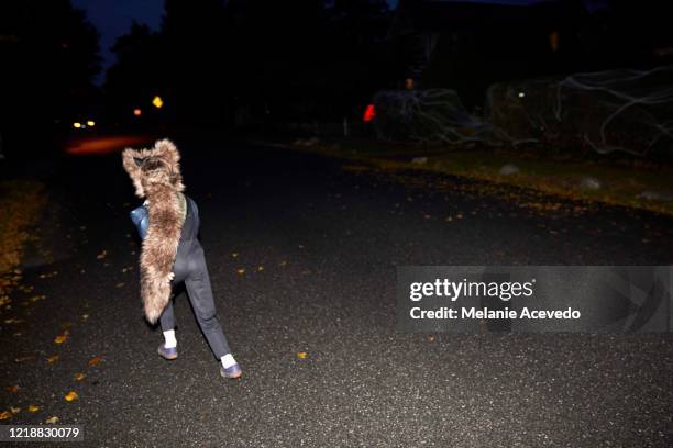 young boy with brown curly hair brown eyes running in street at night time camera flash wearing skunk hat - funny skunk stock pictures, royalty-free photos & images