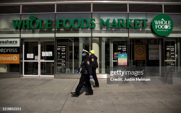 Two New York City Police Department Traffic Enforcement agents walk past the Whole Foods Market on April 14, 2020 in the Brooklyn borough of New York...