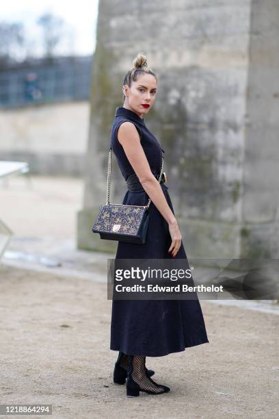 Sira Pevida wears a navy blue dress, a belt, a Dior bag, black mesh pointy boots, outside Dior, during Paris Fashion Week - Womenswear Fall/Winter...