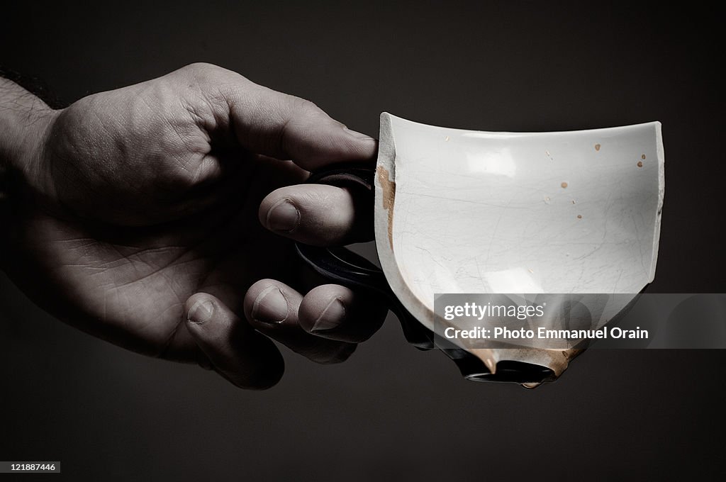 Human hand holding broken cup