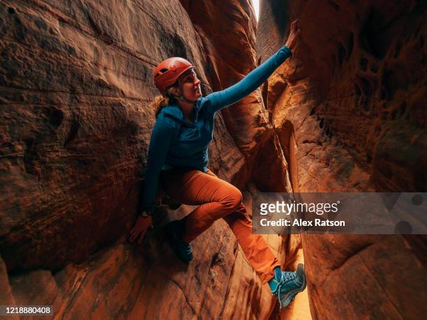 a young women climbs up through slot canyon - canyoneering stock pictures, royalty-free photos & images