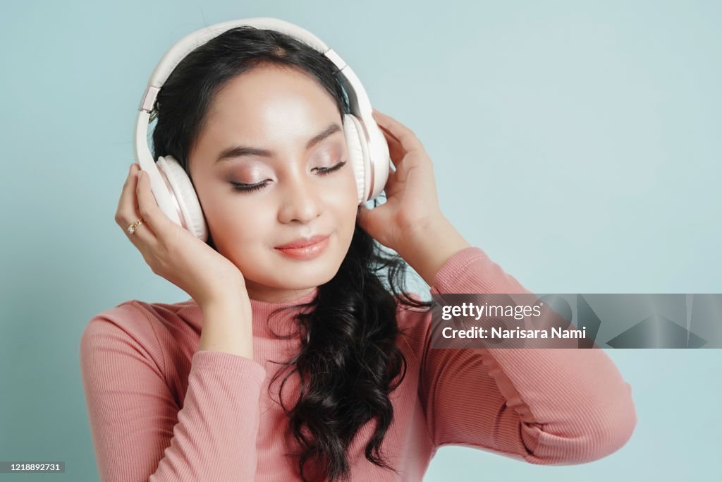 Happy Asian teenage girl listen the music song in wireless headphone from mp3 player technology. relaxation and music lover concept.