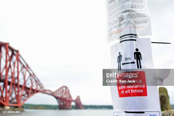 Posters with Covid-19 regulations and advice on a road sign at the Town Pier with the Forth Bridge in the background, after the the Scottish...