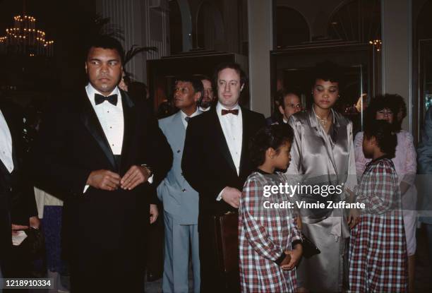 American heavyweight boxer Muhammad Ali , wearing a tuxedo, with his family at an event, circa 1985.