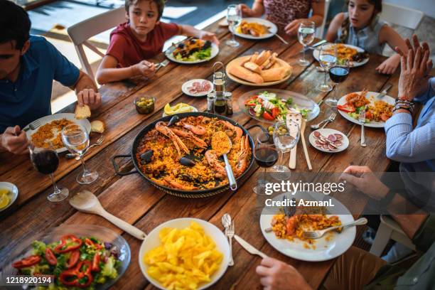 familieleden van meerdere generaties die genieten van paella voor de lunch - paella stockfoto's en -beelden