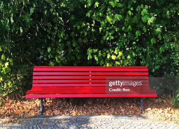 red bench in a public park - banco del parque fotografías e imágenes de stock