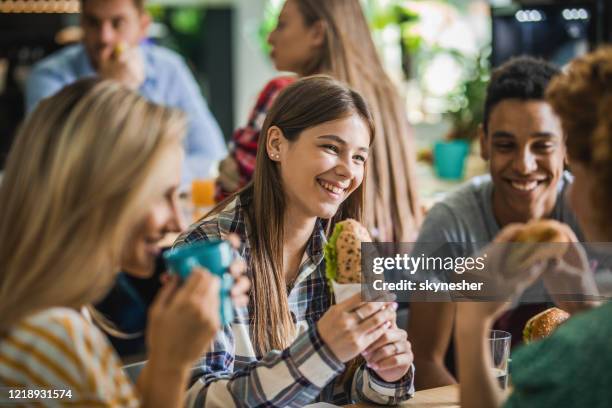 gelukkige studenten die terwijl lunchonderbreking bij cafetaria spreken. - kantine stockfoto's en -beelden