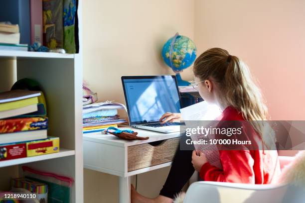 young girl using laptop in bedroom during lockdown - girls learning online imagens e fotografias de stock