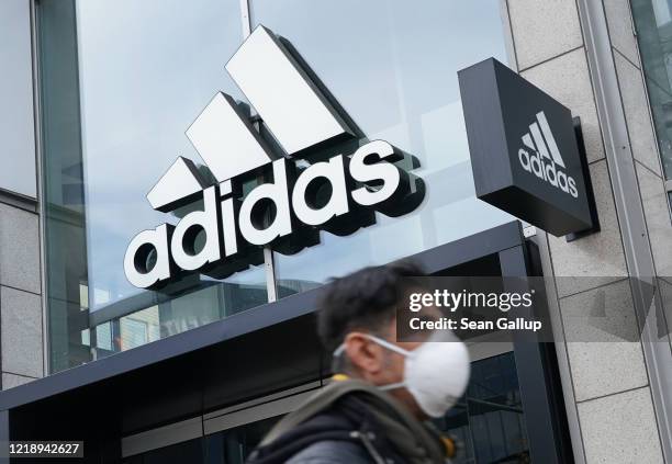 Man wearing a protective face mask, who said he did not mind being photographed, walks past a temporarily closed Adidas store during the coronavirus...