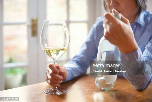 alcohol problems, woman finishing bottle of wine on her own - alcoholic stock-fotos und bilder