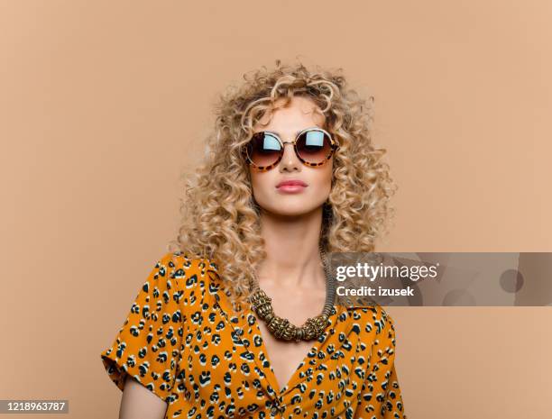 verticale d’été de femme bouclée de cheveux dans la robe d’impression de léopard - sunglasses photos et images de collection